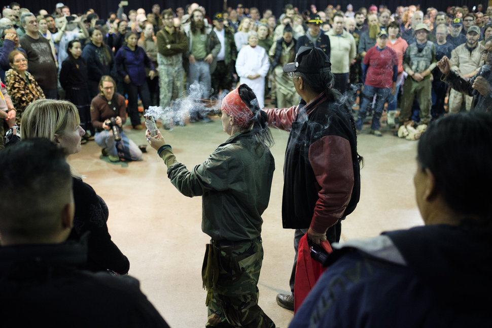 U.S. Army Veterans Tih Kobolson, left, and Aloysious Bell, walk around with a ceremonial smudge stick and feathers during a forgiveness ceremony at the Four Prairie Knights Casino & Resort on the Standing Rock Sioux Reservation on Monday, Dec. 5, 2016.